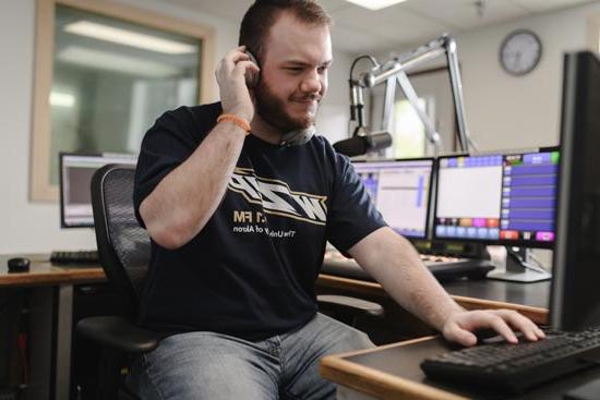 Two student announcers working in the UA WZIP radio studio during an on-air production.