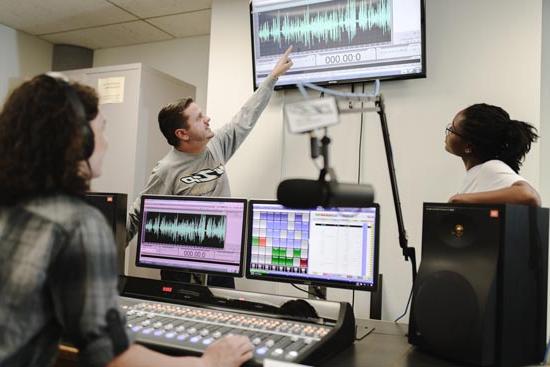 Two student announcers working in the UA WZIP radio studio during an on-air production.