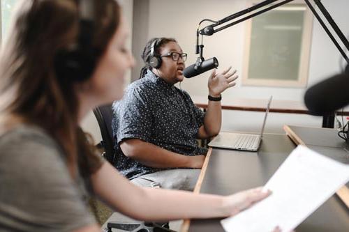 Two student announcers working in the UA WZIP radio studio during an on-air production.