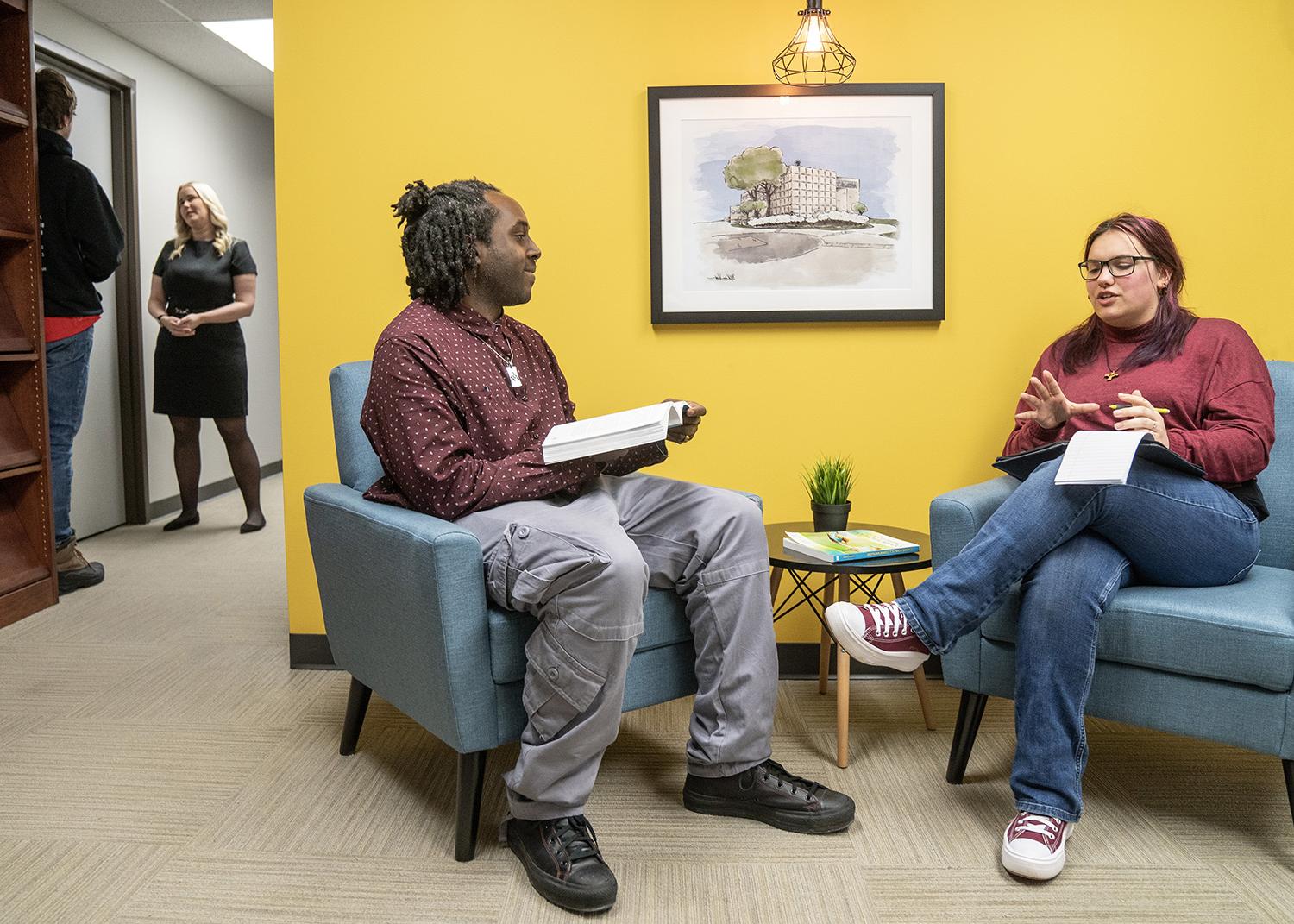 Two communication students work on a project in the library.